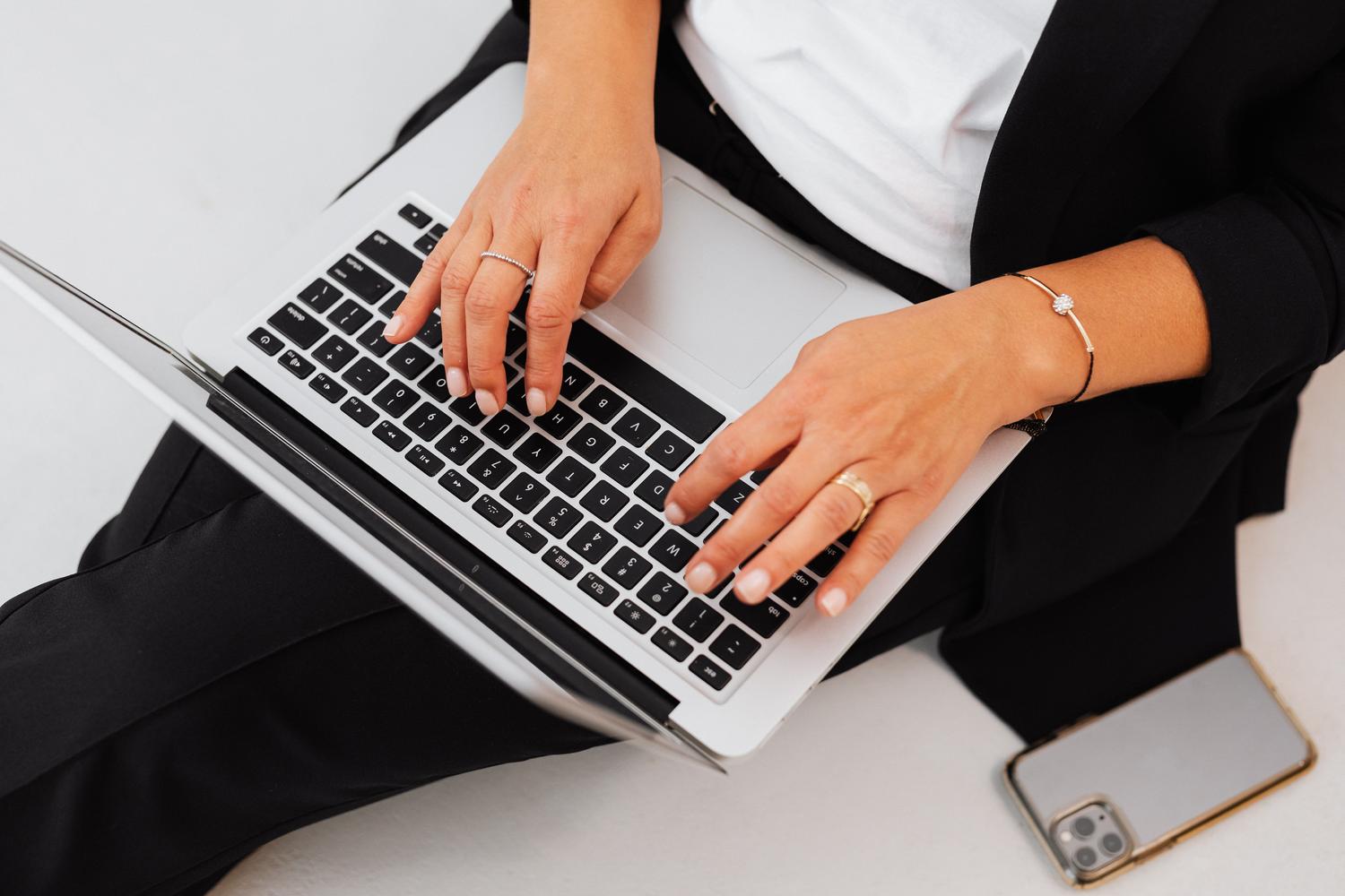 Primer plano de una profesional trabajando con portátil y smartphone, simbolizando la eficiencia de la administración electrónica.