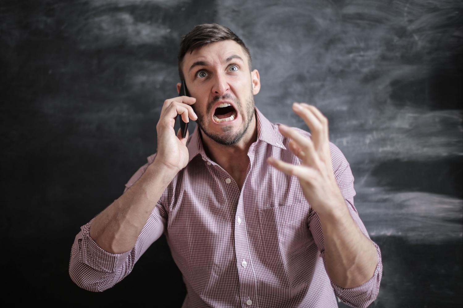 Hombre frustrado intentando usar un smartphone con la pantalla congelada