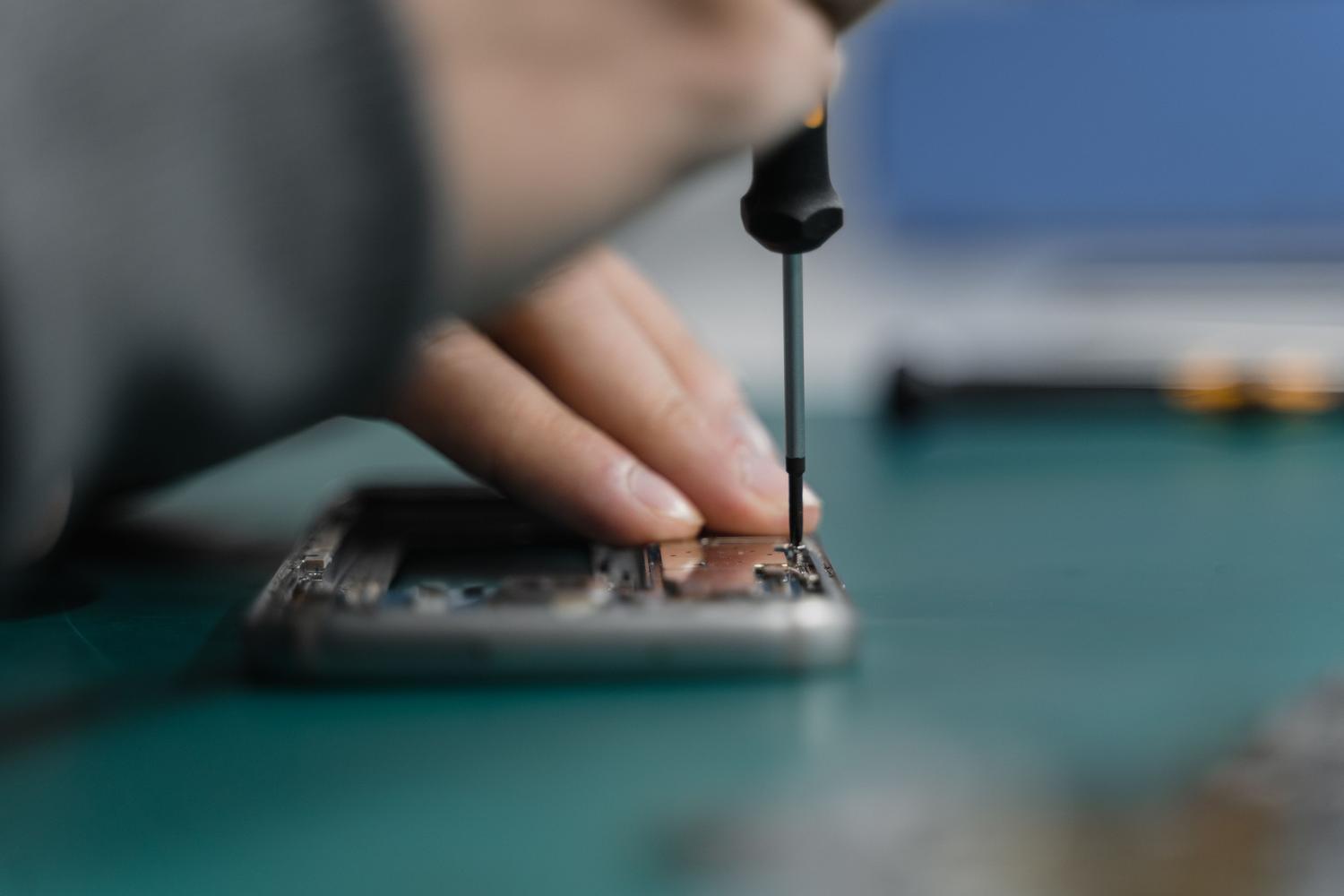 Técnico especializado reparando la pantalla de un smartphone con herramientas de precisión