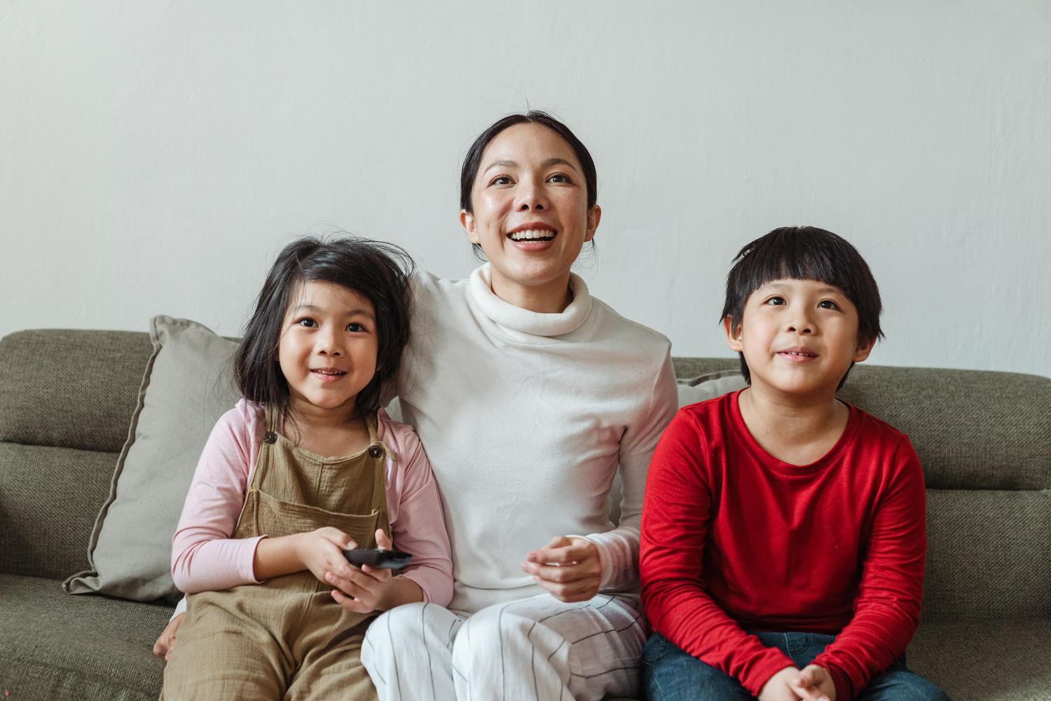 Una madre y sus hijos emocionados viendo una película en la televisión, destacando la gestión de perfiles familiares.