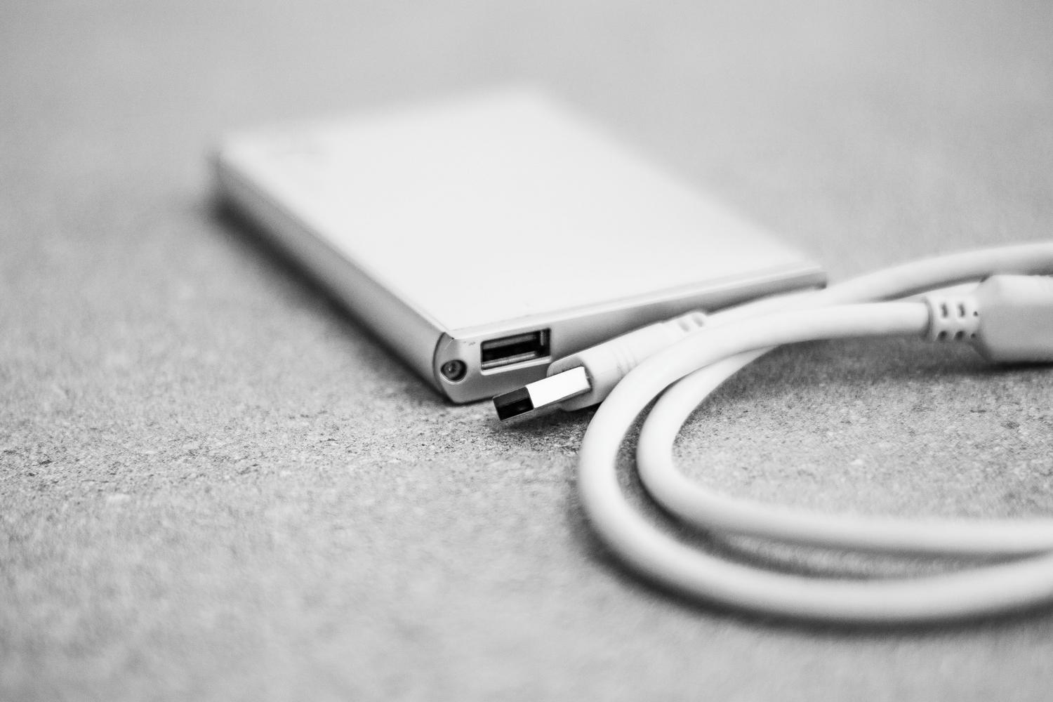 Imagen minimalista en blanco y negro de la conexión USB de un disco duro, ideal para explicar aspectos técnicos como el sistema de archivos NTFS.