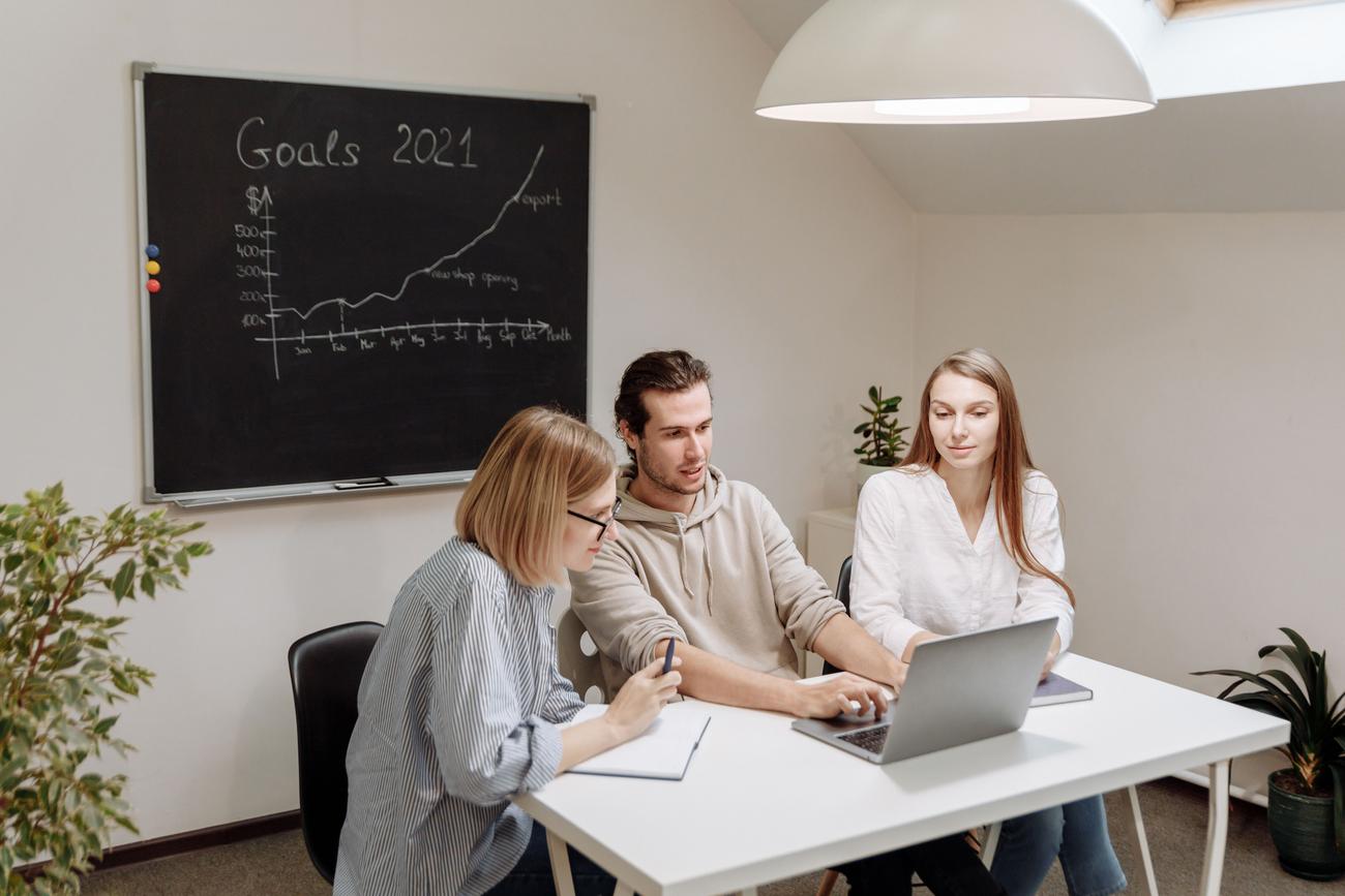 Equipo de profesionales colaborando en una oficina iluminada, revisando la planificación de un proyecto en un ordenador.