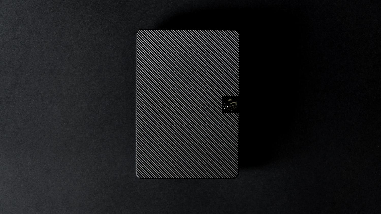 Imagen detallada de un disco duro externo moderno y elegante sobre un fondo oscuro