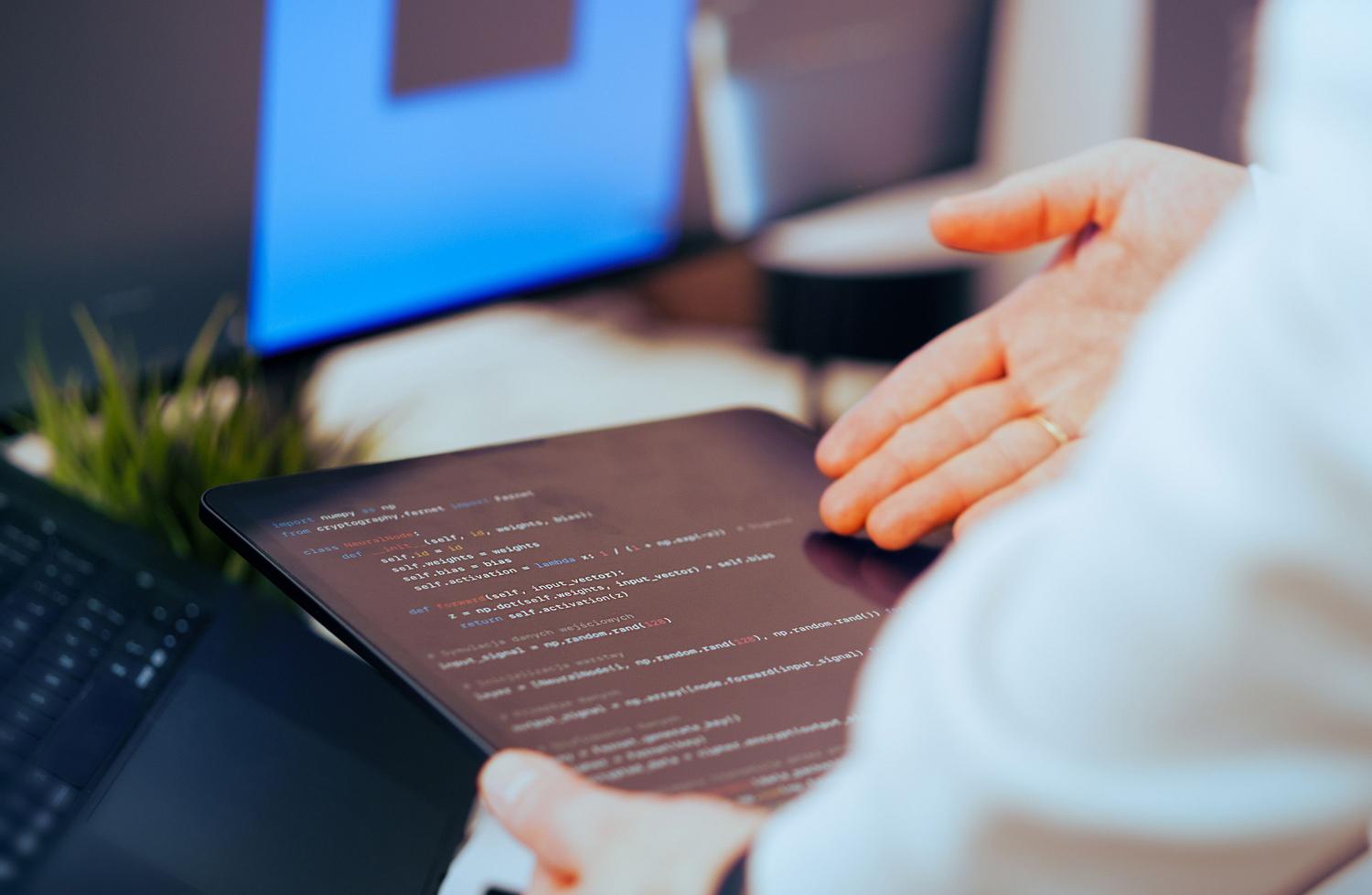 Un desarrollador de software analizando código en una tablet, simbolizando la supervisión humana y el control técnico sobre los algoritmos.