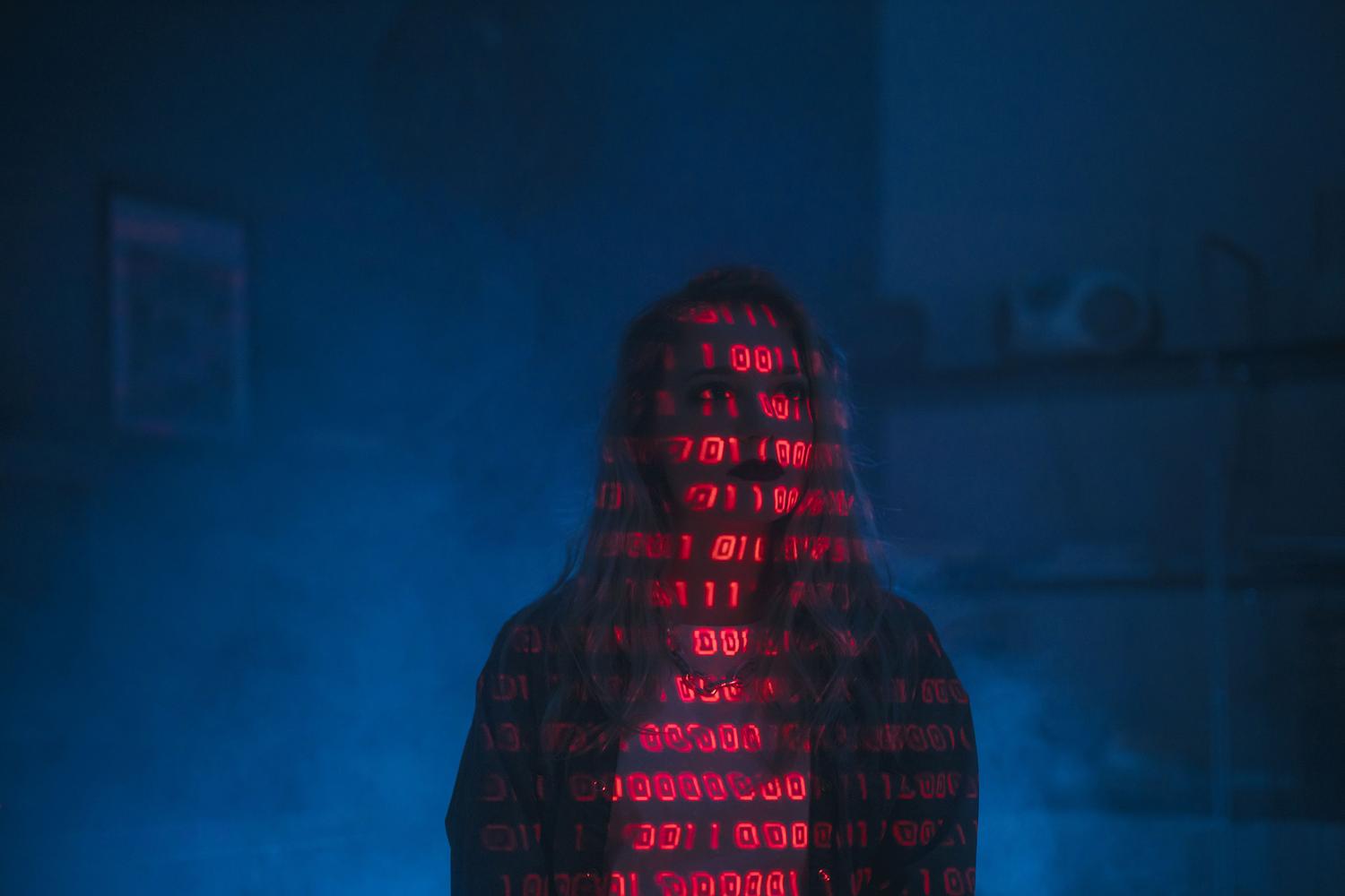 Silueta humana con código binario rojo proyectado, ilustrando las amenazas de ciberseguridad y la urgencia de proteger los sistemas de IA.