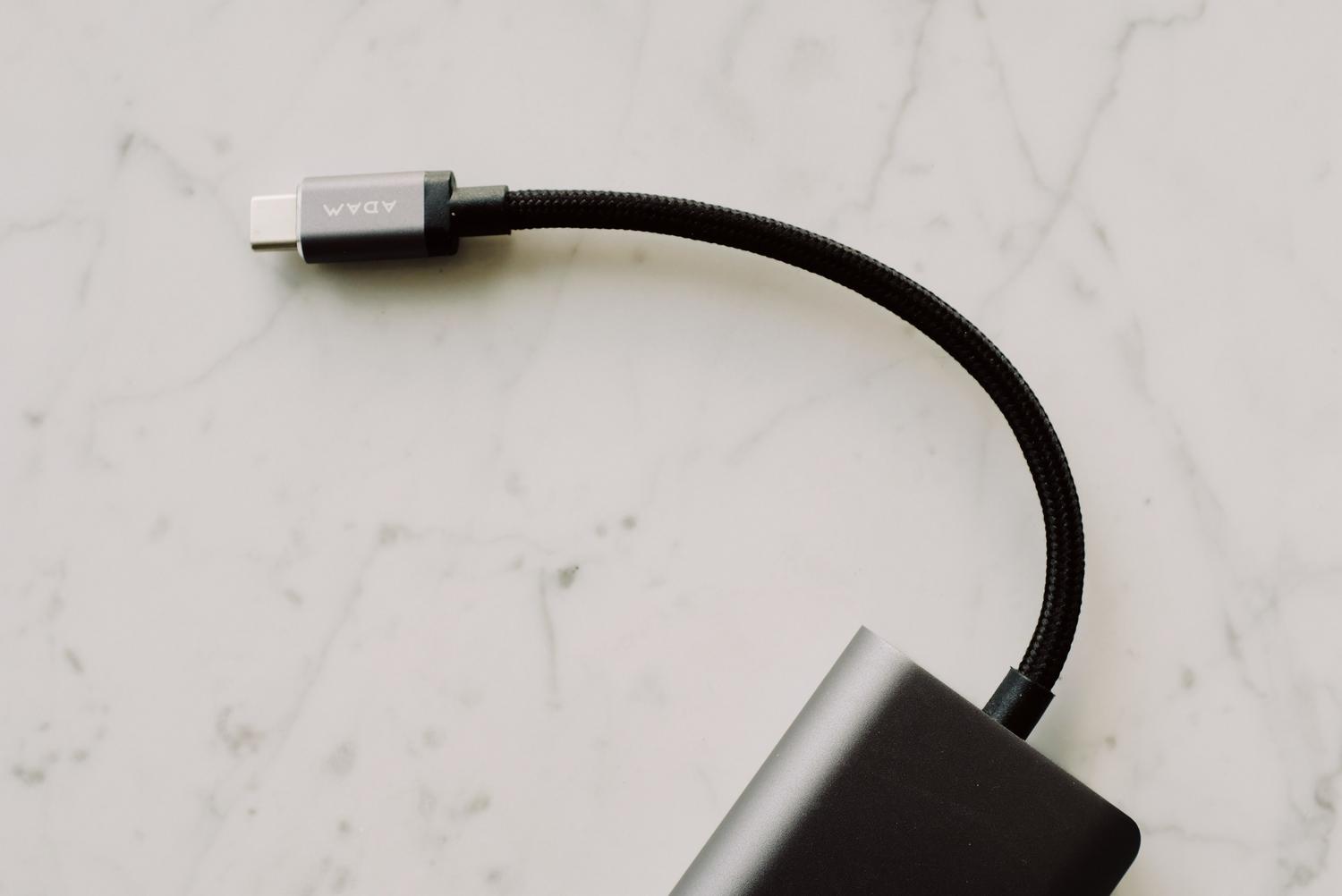 Cable USB-C trenzado de alta calidad sobre superficie de mármol, destacando la importancia de usar cables resistentes para una conexión estable.