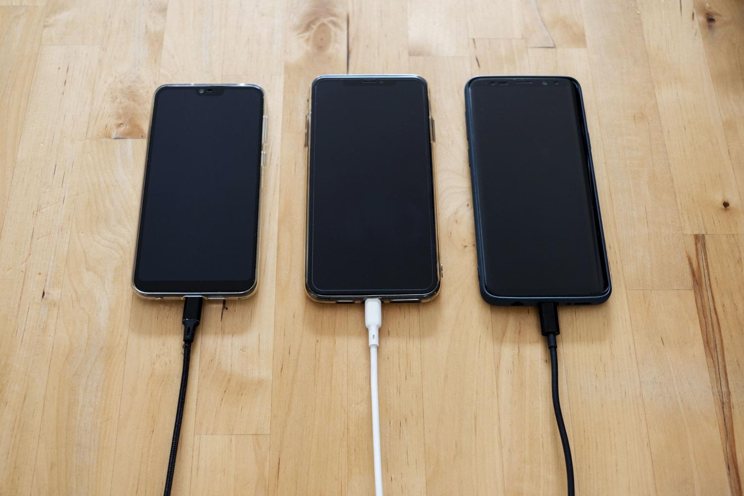 Varios smartphones modernos cargándose simultáneamente sobre una mesa de madera, representando la fase de preparación para una migración de datos.