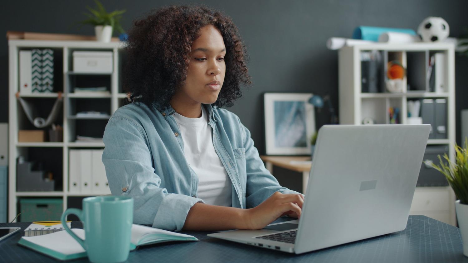 Mujer concentrada en su laptop en un escritorio organizado, ilustrando el modo de enfoque y productividad.