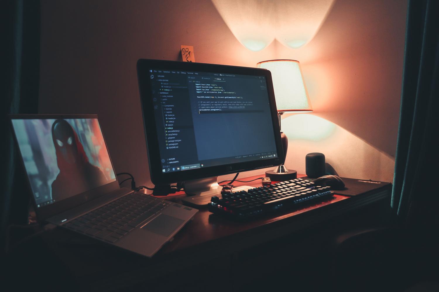 Centro de mando de programador con doble pantalla, teclado mecánico y luz cálida acogedora.