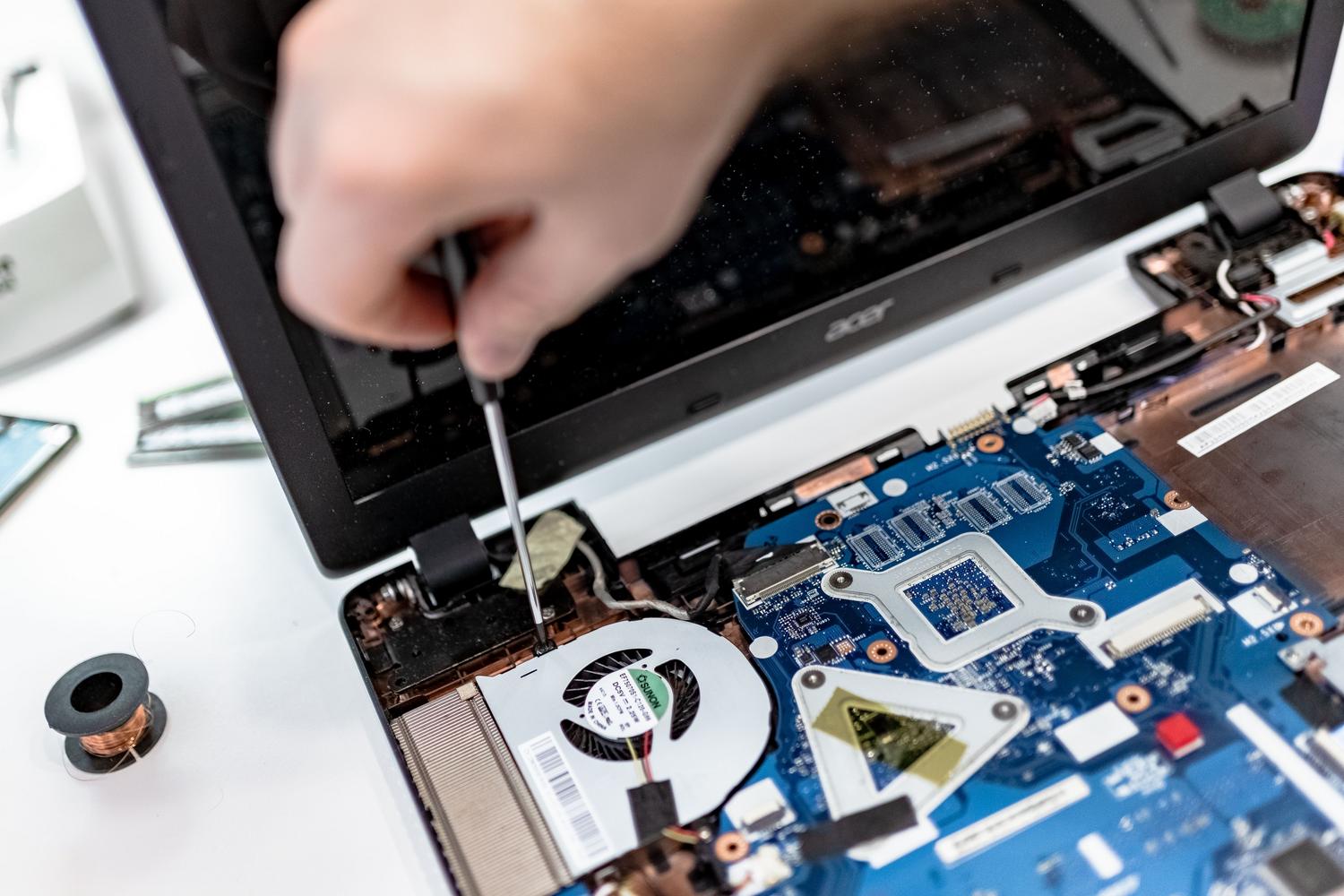 Técnico especializado reparando la placa base de un ordenador portátil, representando el mantenimiento profundo del sistema.