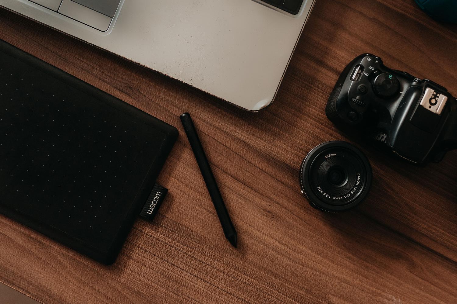 Vista superior de un escritorio de fotografía con cámara, tableta gráfica y ordenador portátil.