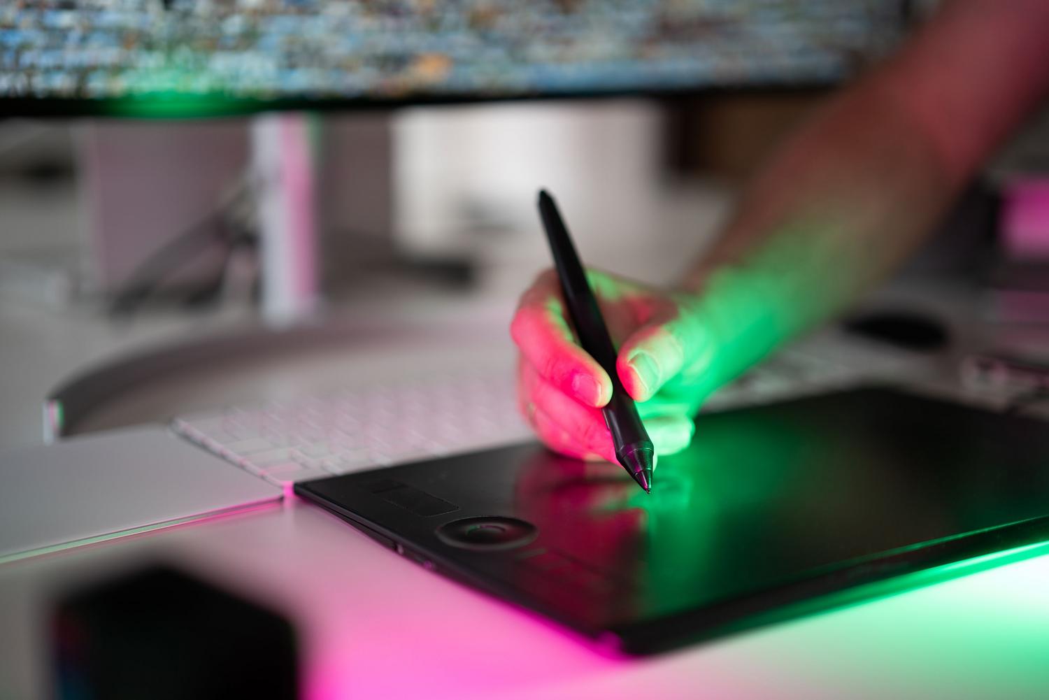 Mano utilizando un lápiz digital sobre una tableta gráfica para retoque preciso de imágenes.