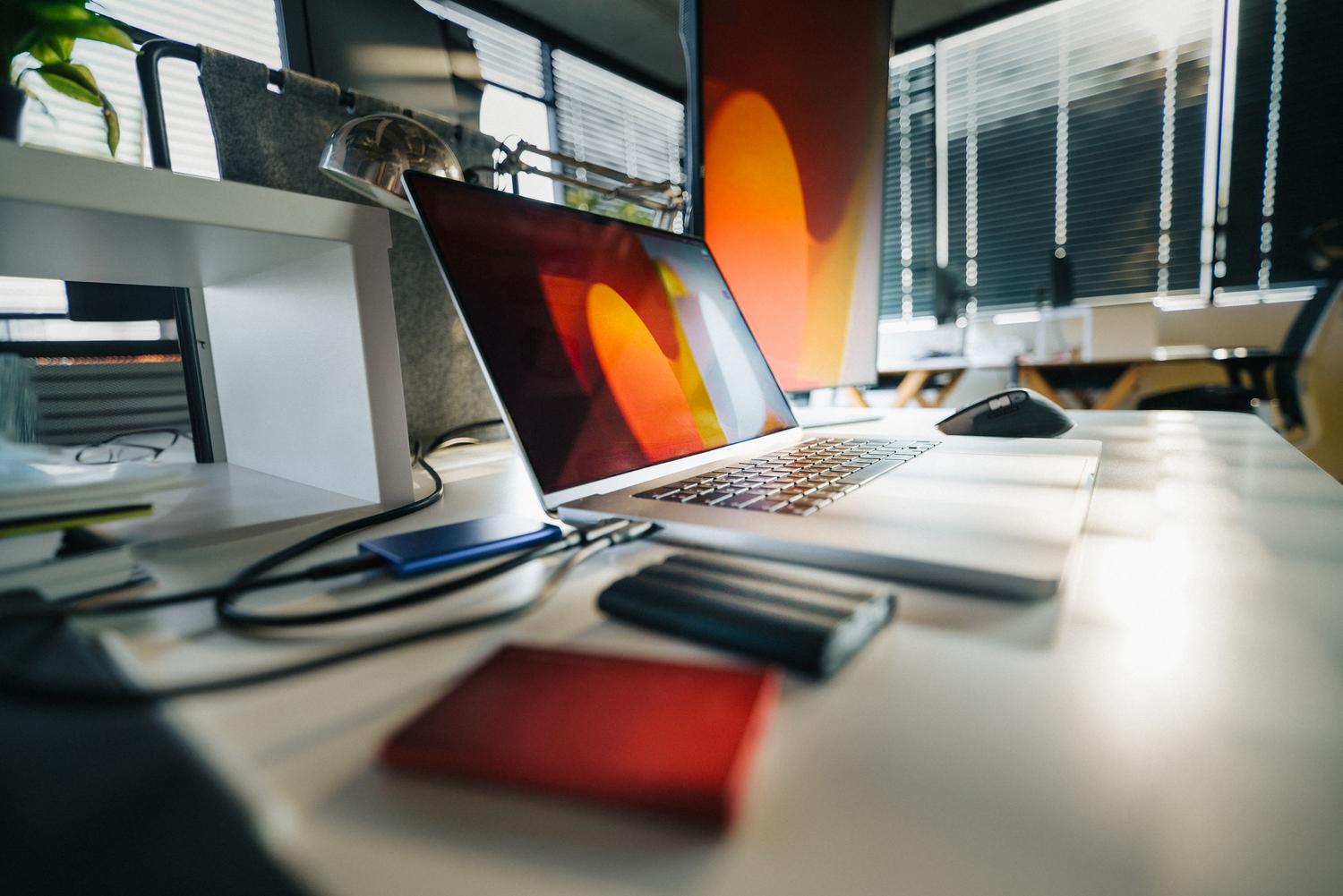 Espacio de trabajo moderno con un portátil y varios discos duros externos para la gestión de datos profesionales.