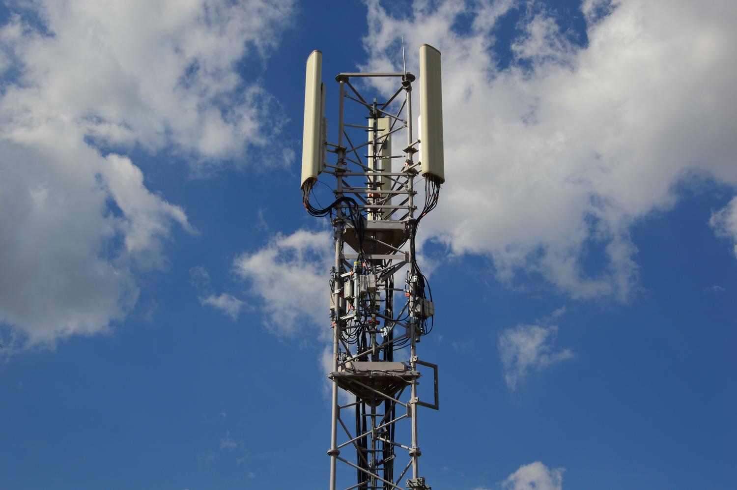 Torre de comunicación celular bajo un cielo azul, representando la infraestructura de la señal de red móvil