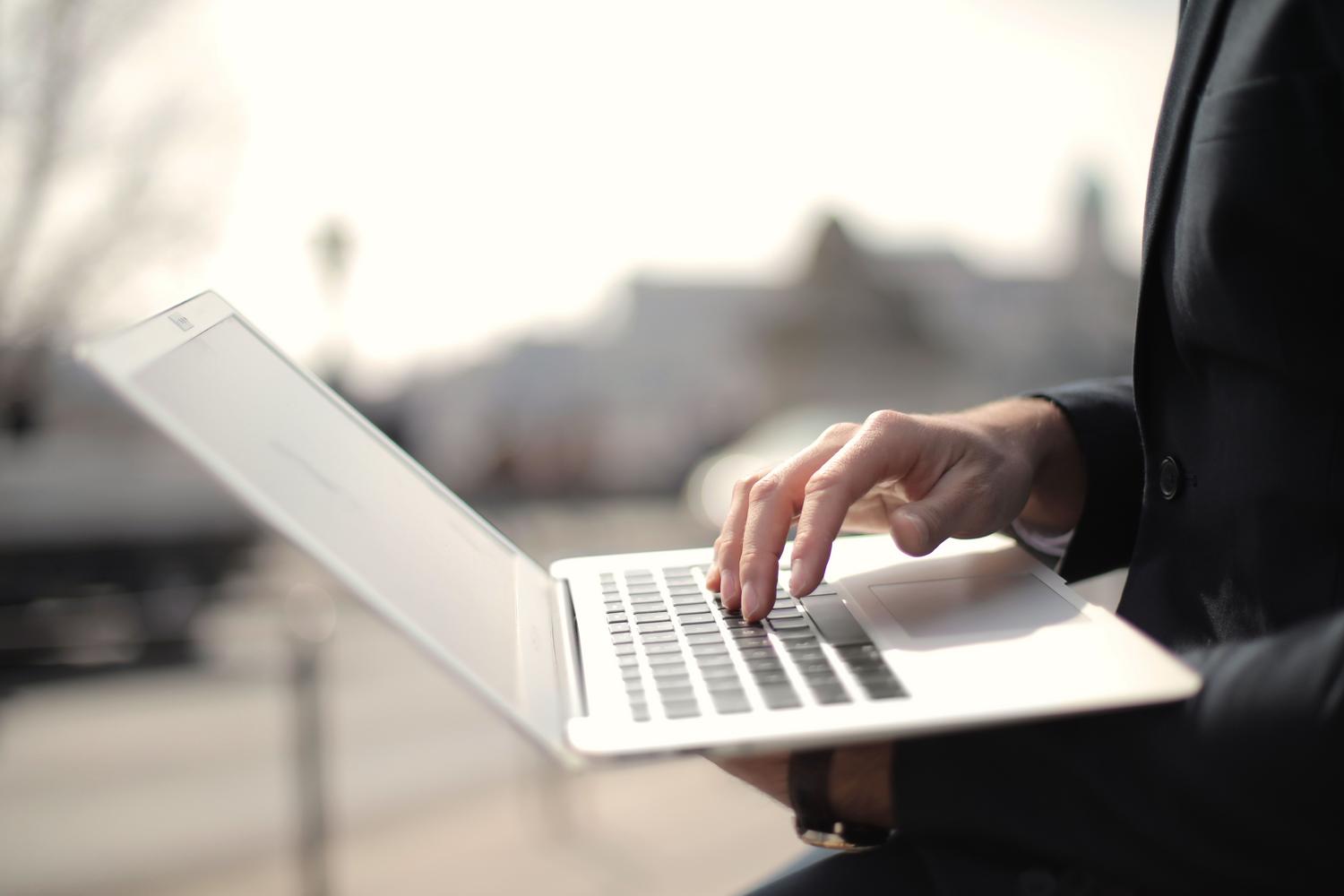 Profesional trabajando con un portátil en un entorno exterior, resaltando la importancia de la autonomía de la batería en dispositivos móviles.