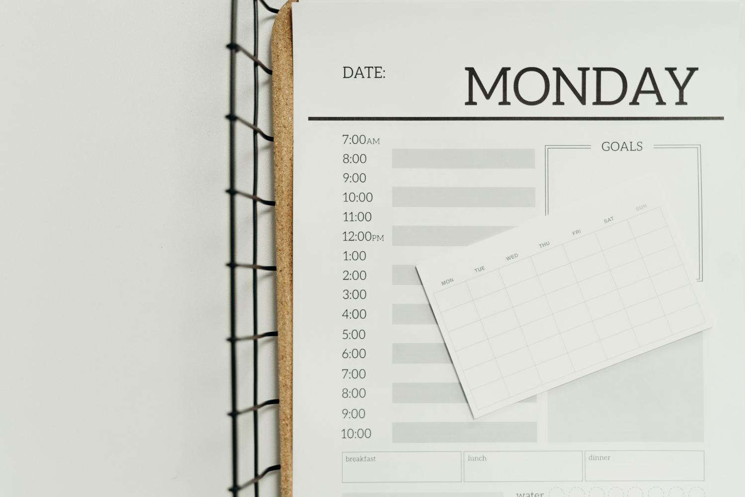 Vista cenital de un planificador diario minimalista con secciones dedicadas a metas y horario, ideal para la gestión de tareas.
