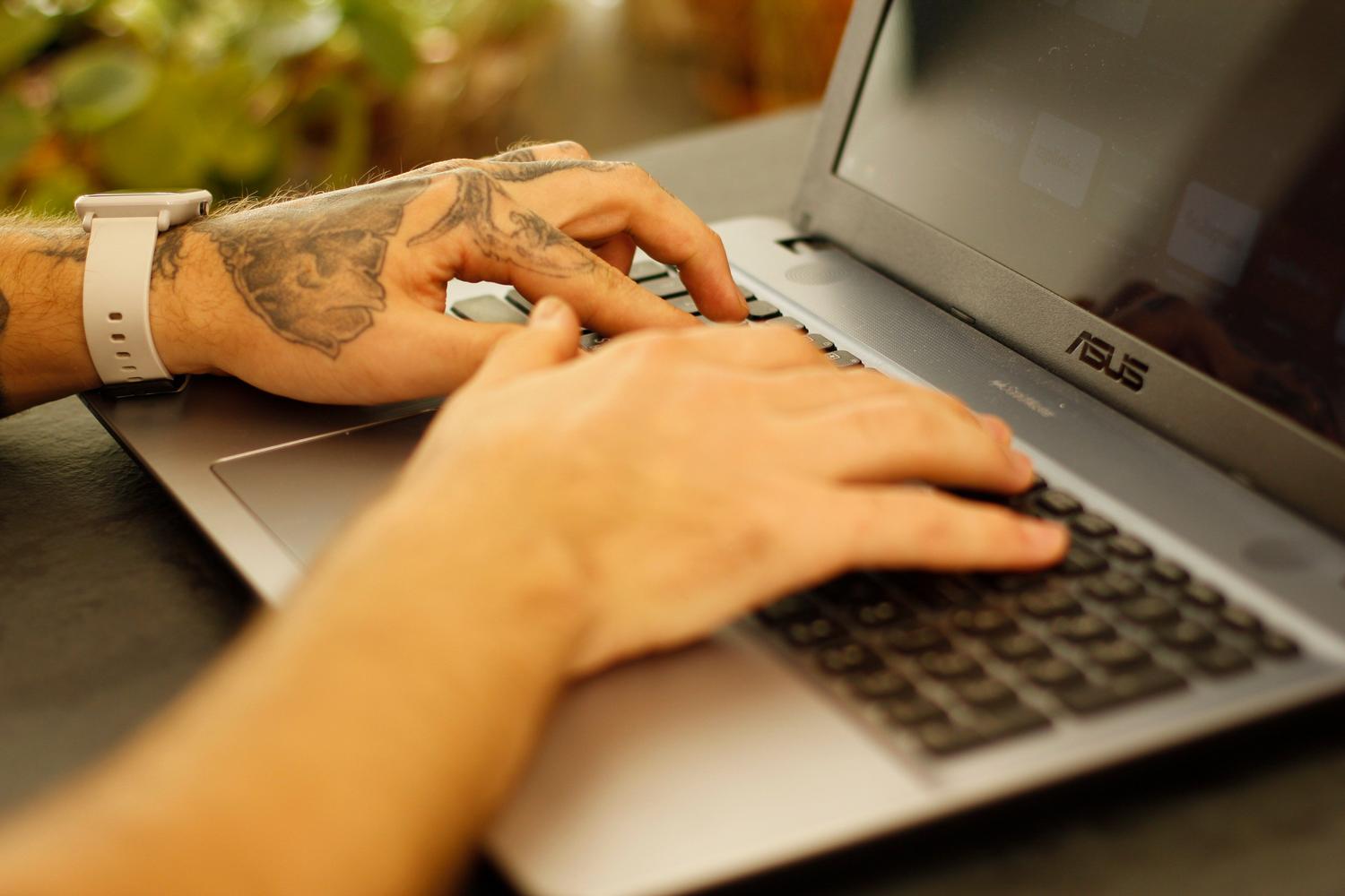 Detalle de manos escribiendo en el teclado de un ordenador portátil, imagen genérica de productividad digital.