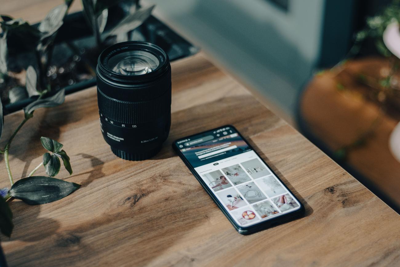 Configuración creativa de fotografía móvil con un smartphone y un objetivo de cámara profesional sobre una mesa de madera.