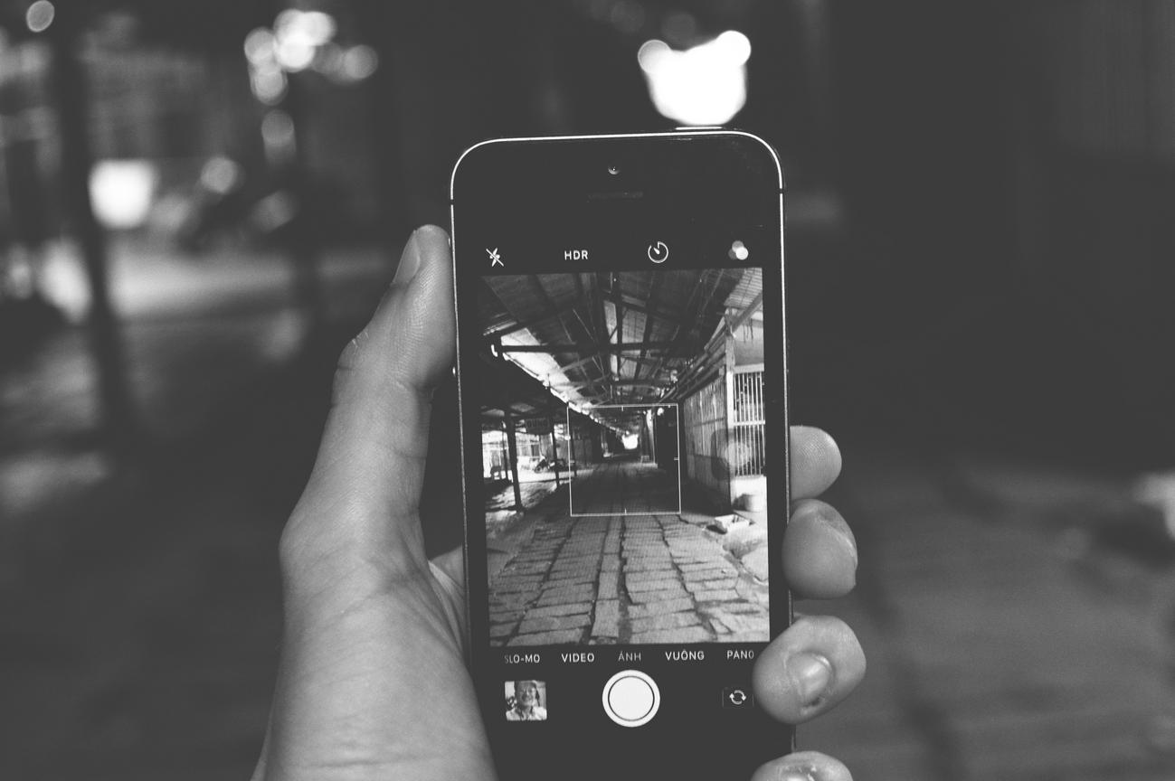Imagen artística en blanco y negro de un smartphone mostrando una fotografía urbana, representando el resultado final de un proceso de retoque.