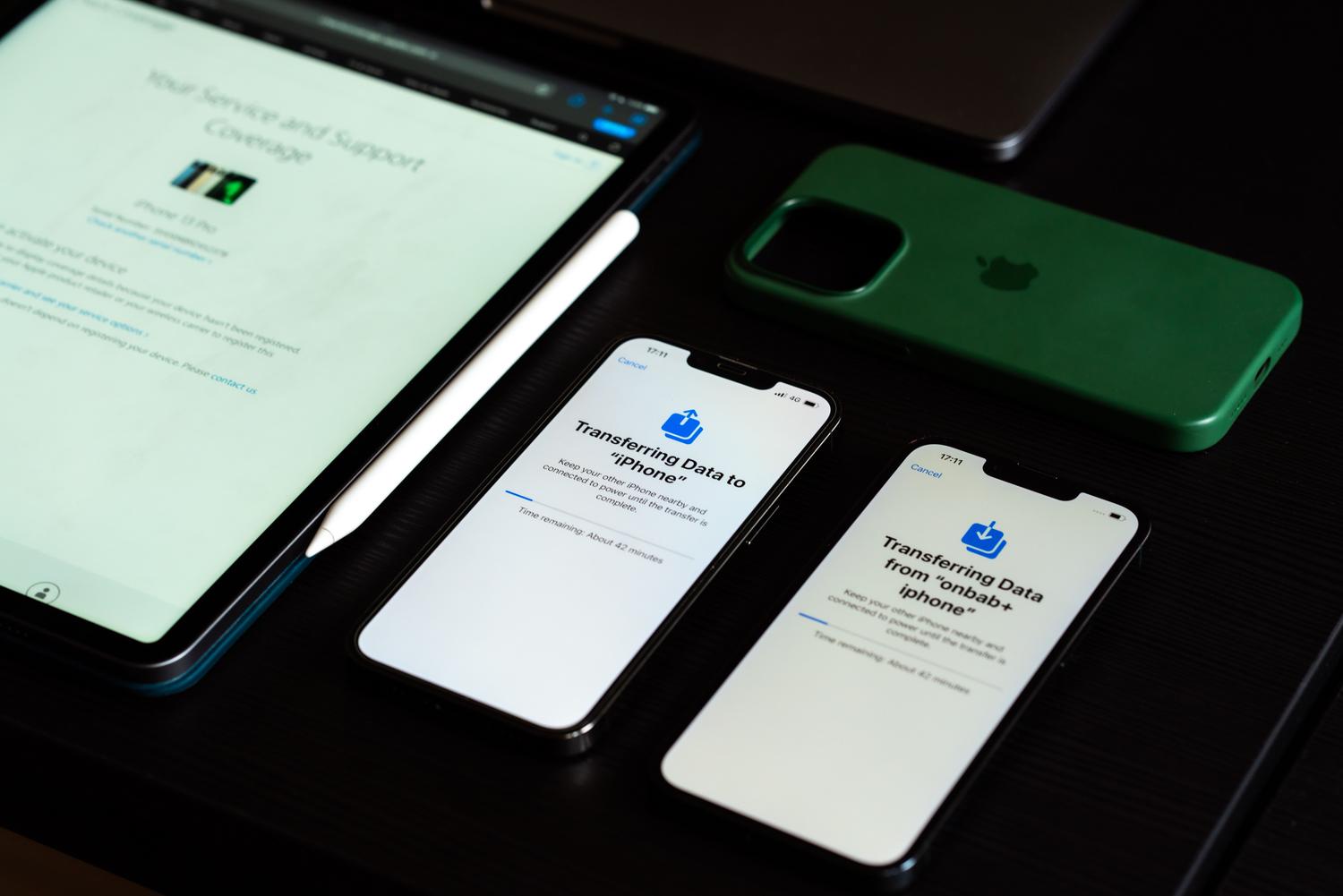 Vista cenital de varios dispositivos Apple en un escritorio, destacando el proceso de transferencia de datos inalámbricos.