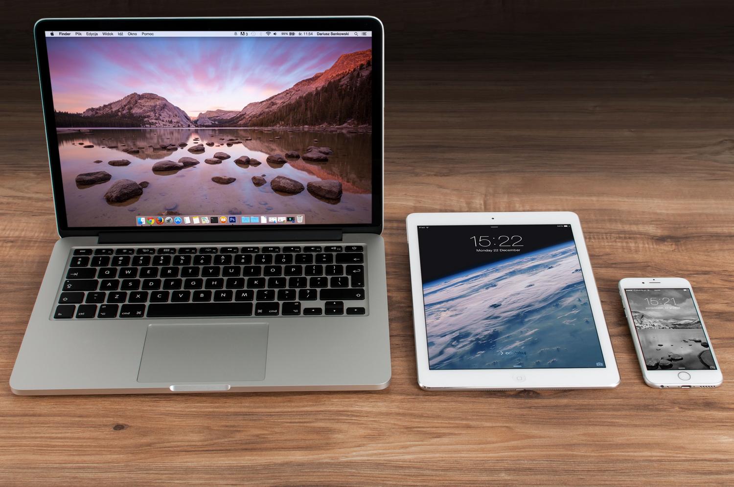 MacBook Pro, iPad e iPhone dispuestos en un escritorio de madera, representando el ecosistema de Apple.