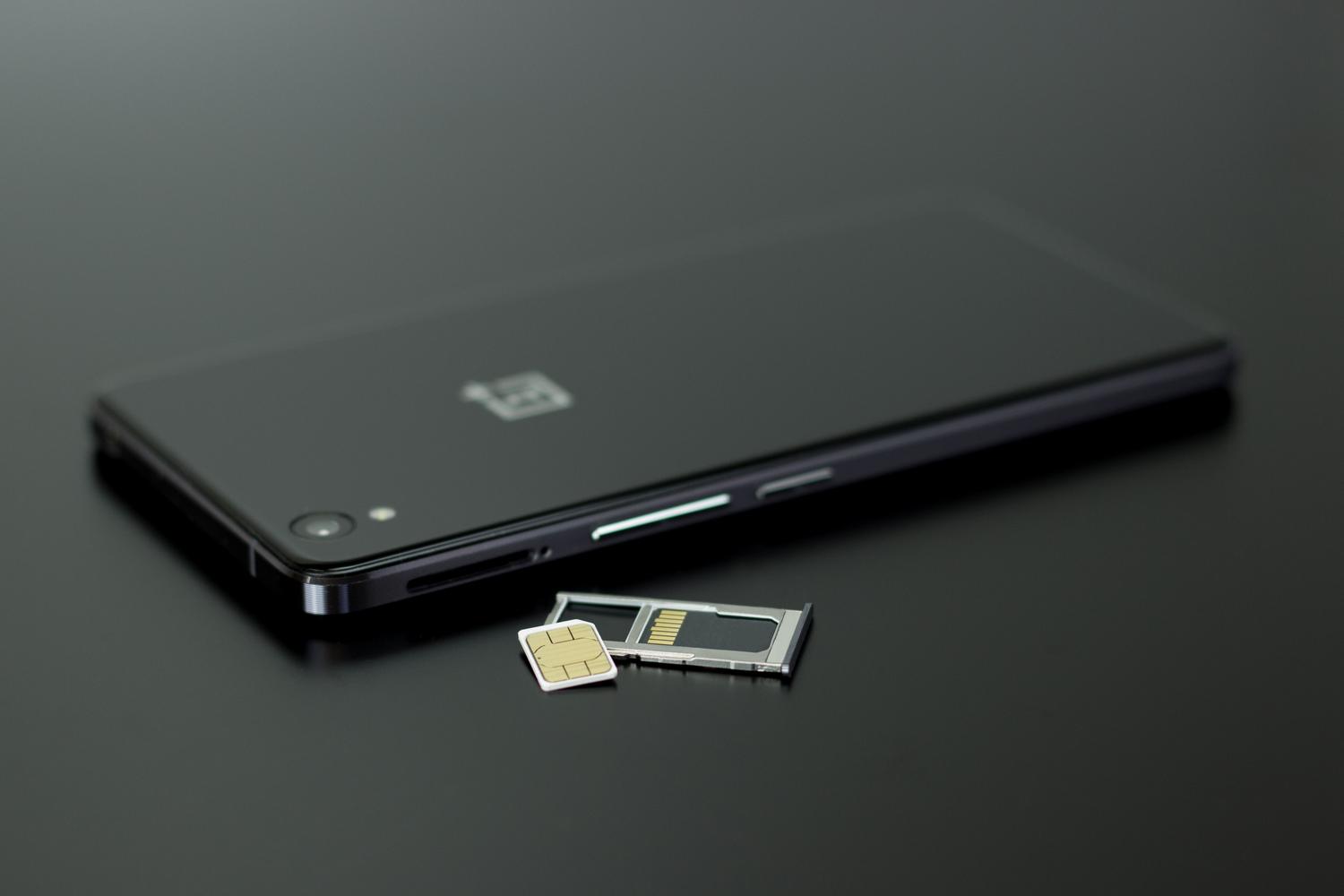 Smartphone negro sobre una mesa con su bandeja de SIM y una tarjeta microSD al lado, mostrando cómo se integra la memoria externa en el dispositivo.