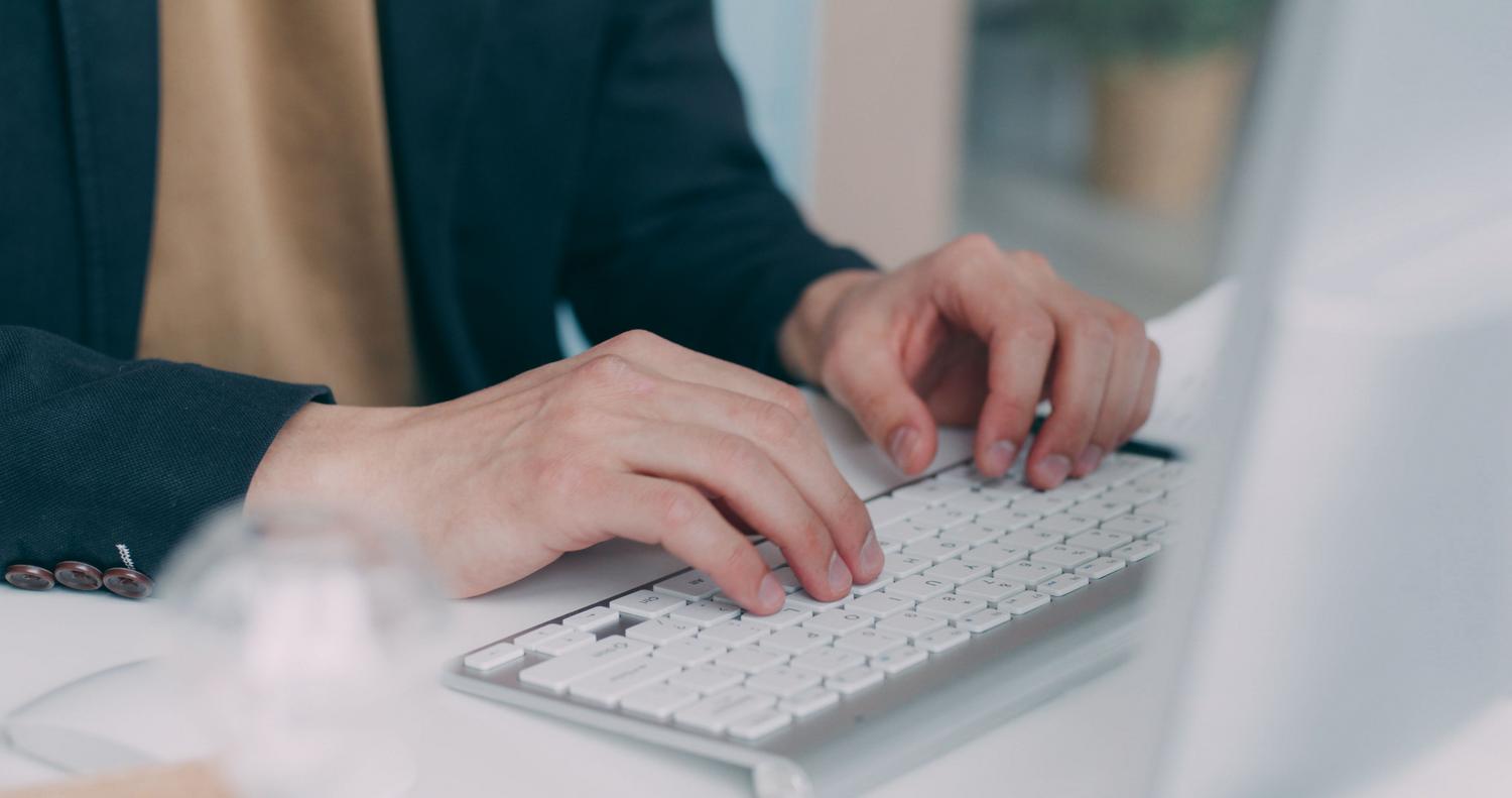 Primer plano de manos escribiendo en un teclado profesional, enfocado en la precisión y el flujo de trabajo de traducción.