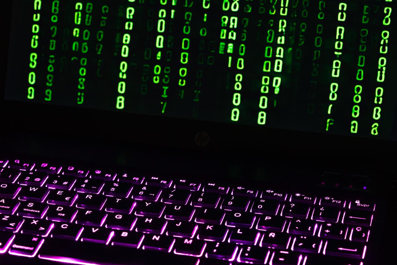 Primer plano de un teclado de laptop con código digital verde en la pantalla, simbolizando la naturaleza técnica y el rastreo de telemetría del sistema.