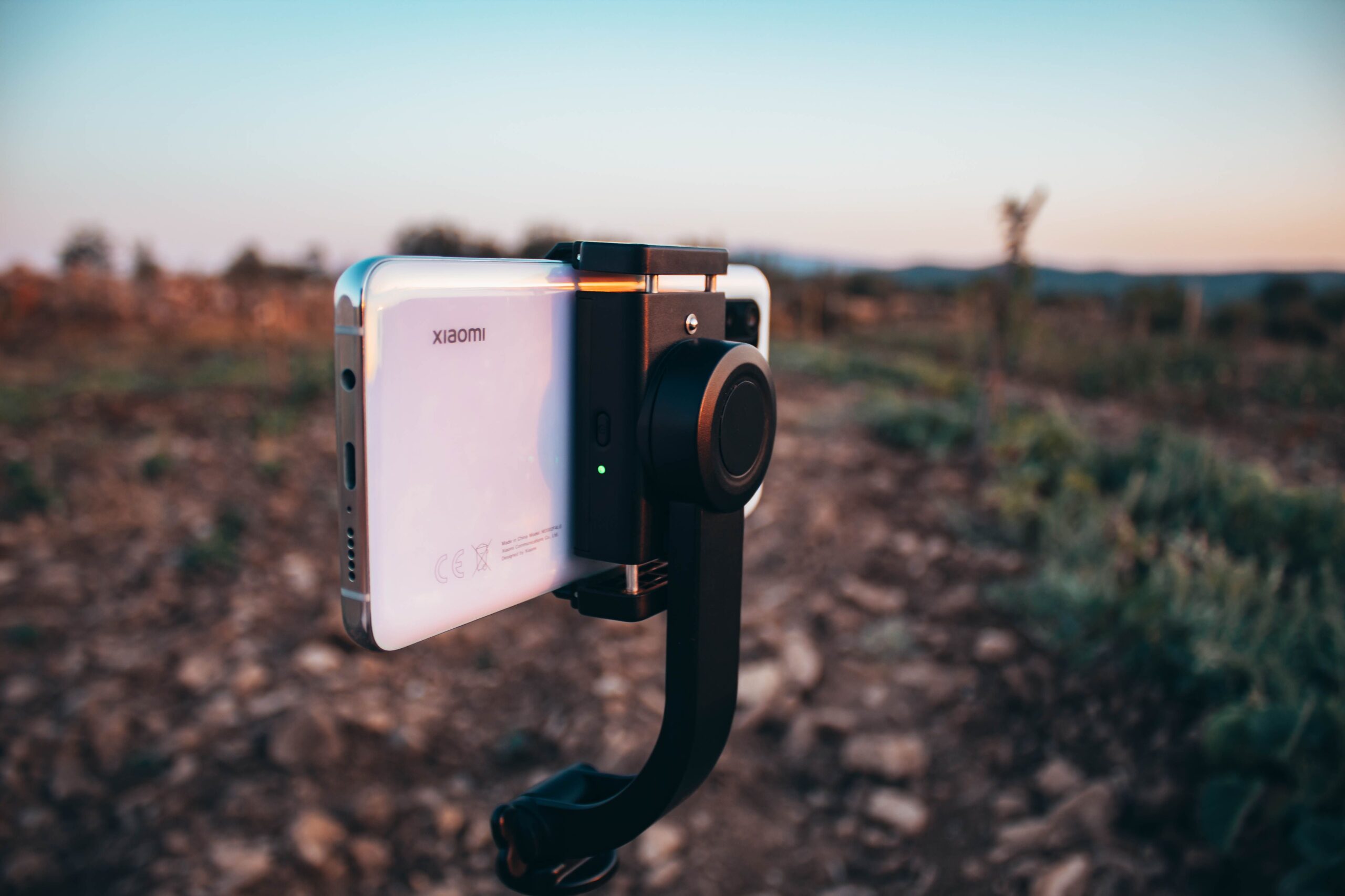 Smartphone montado en un estabilizador gimbal durante un atardecer, ideal para ilustrar la grabación de vídeo profesional con móvil.
