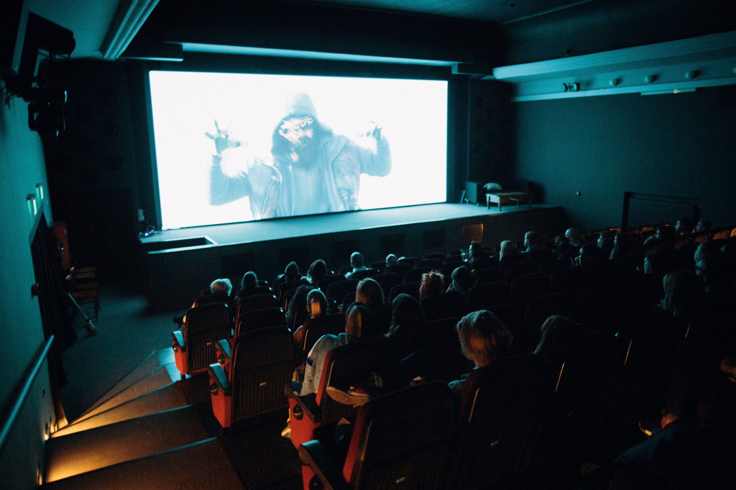 Sala de cine llena de espectadores disfrutando de una película en una pantalla de gran formato.