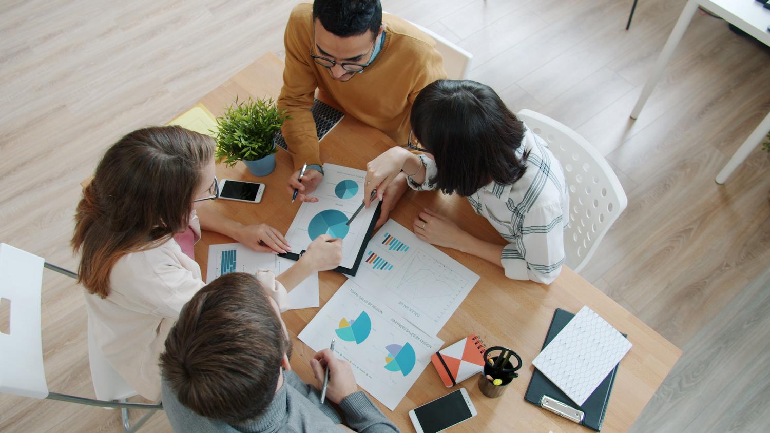 Equipo de profesionales analizando gráficos y datos en una reunión, ideal para representar la colaboración y el análisis de documentos complejos.