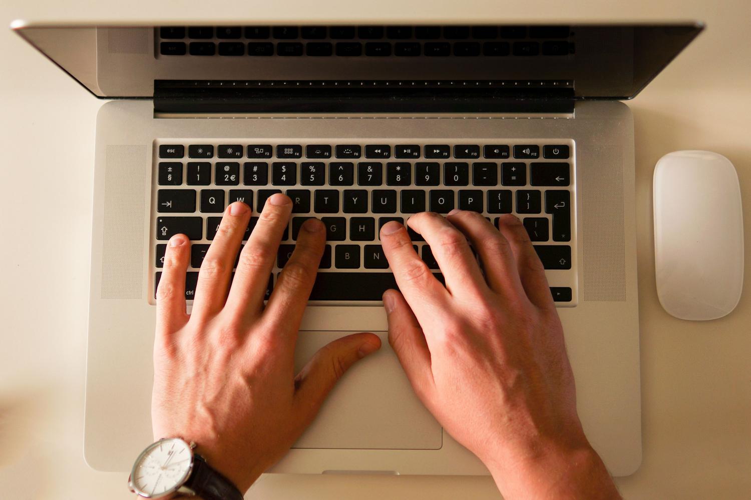 Primer plano de manos utilizando un teclado de ordenador para crear listas de reproducción personalizadas.