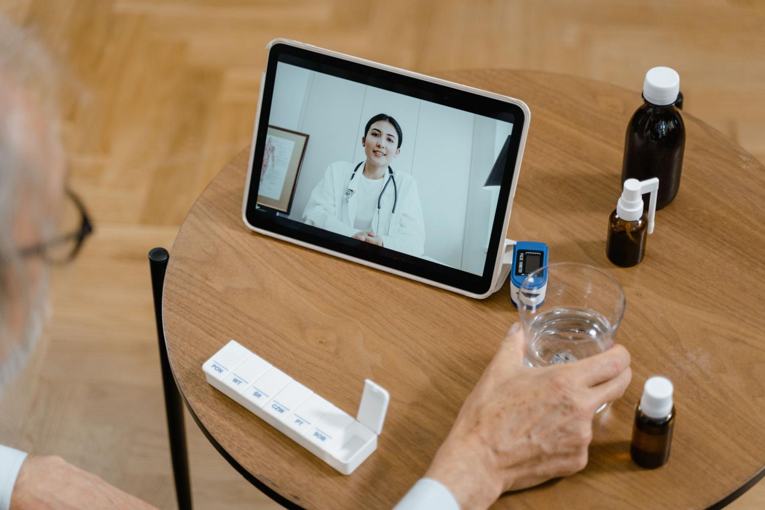 Paciente adulto mayor realizando una videoconsulta médica desde casa utilizando una tablet.