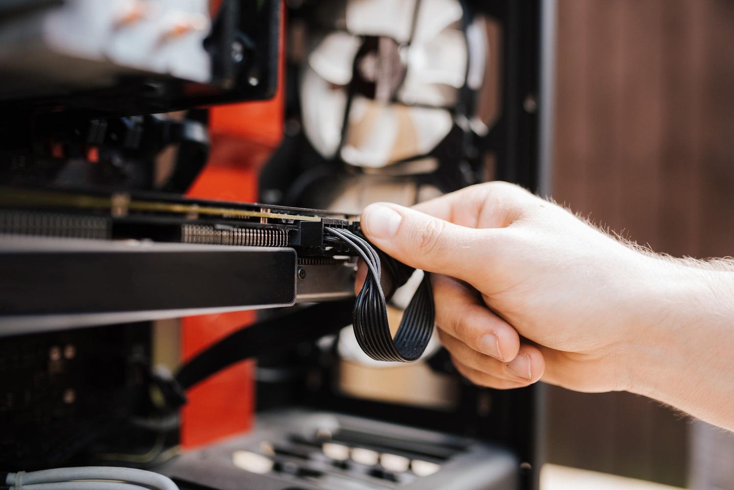 Técnico manipulando los cables internos de una torre de ordenador para optimizar el hardware
