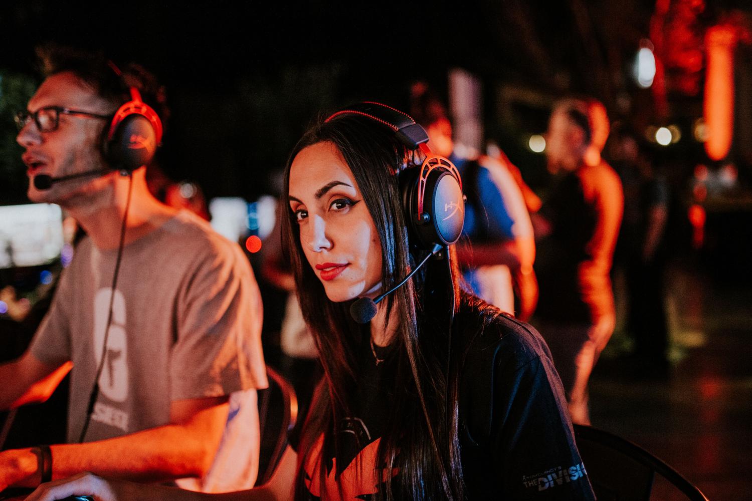 Mujer joven con auriculares de gaming concentrada, ilustrando la participación individual dentro de un grupo cooperativo.
