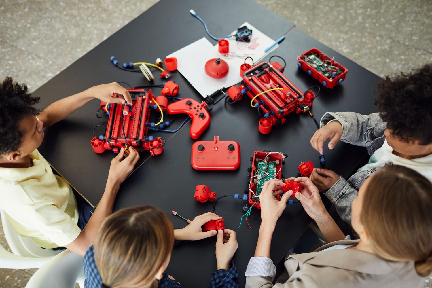 Docente guiando a alumnos en la construcción de robots educativos en un entorno colaborativo.