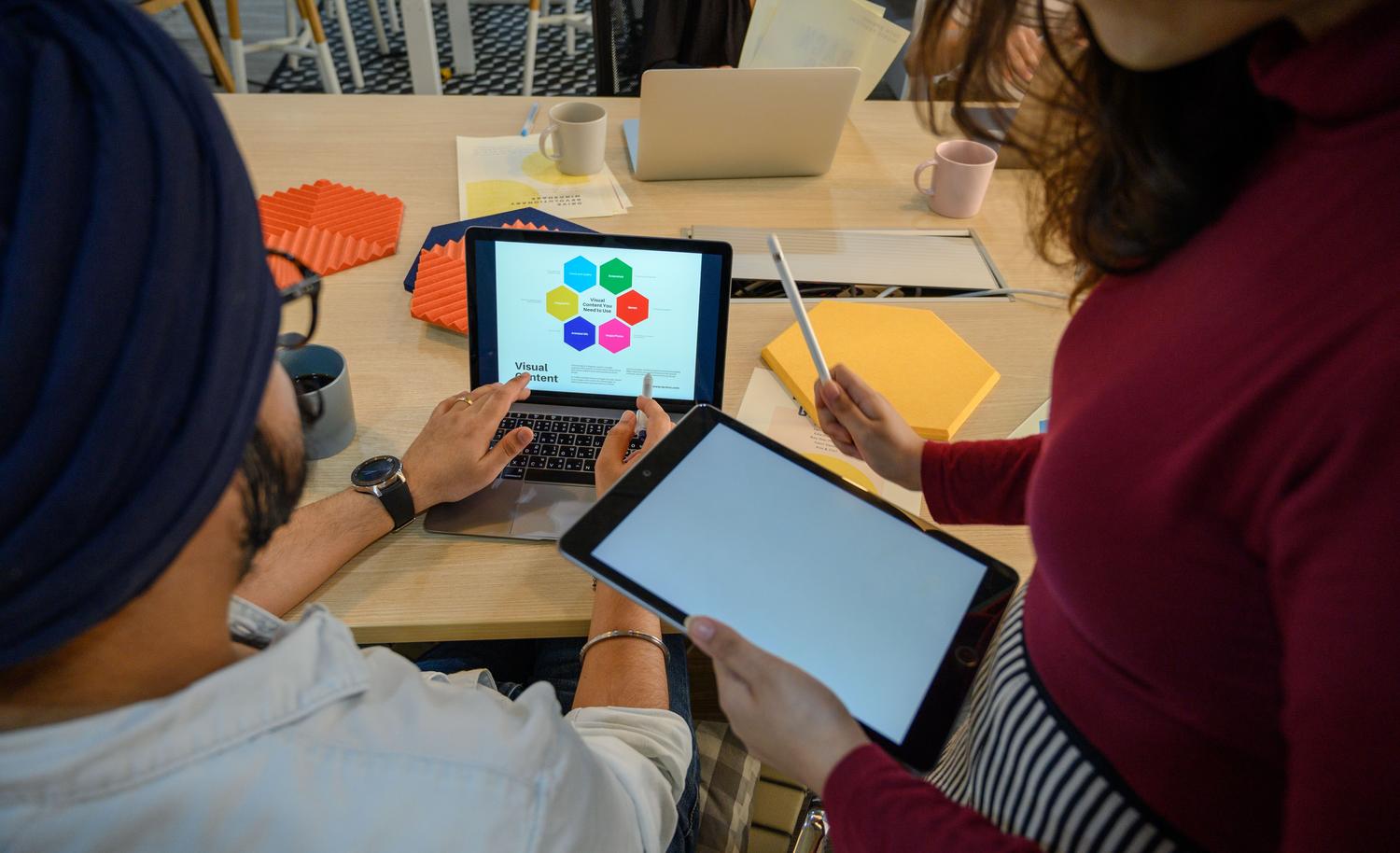Reunión creativa con dispositivos digitales, resaltando la agilidad operativa y la innovación en el entorno corporativo.