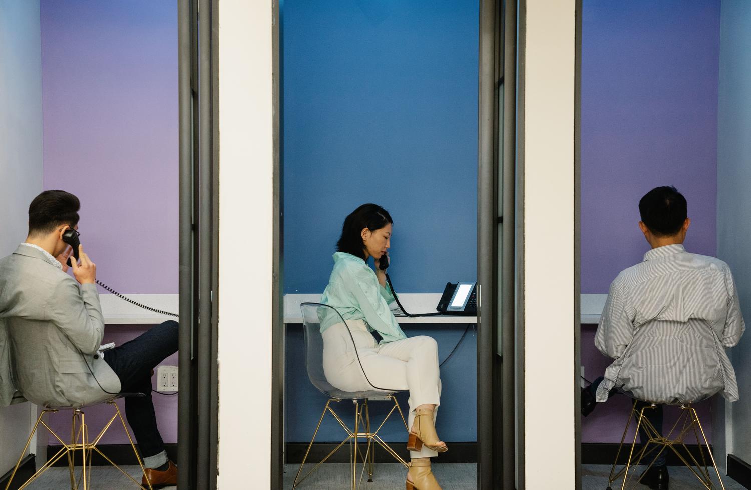 Profesionales utilizando cabinas acústicas para llamadas telefónicas en una oficina moderna, enfatizando la privacidad y el entorno corporativo.