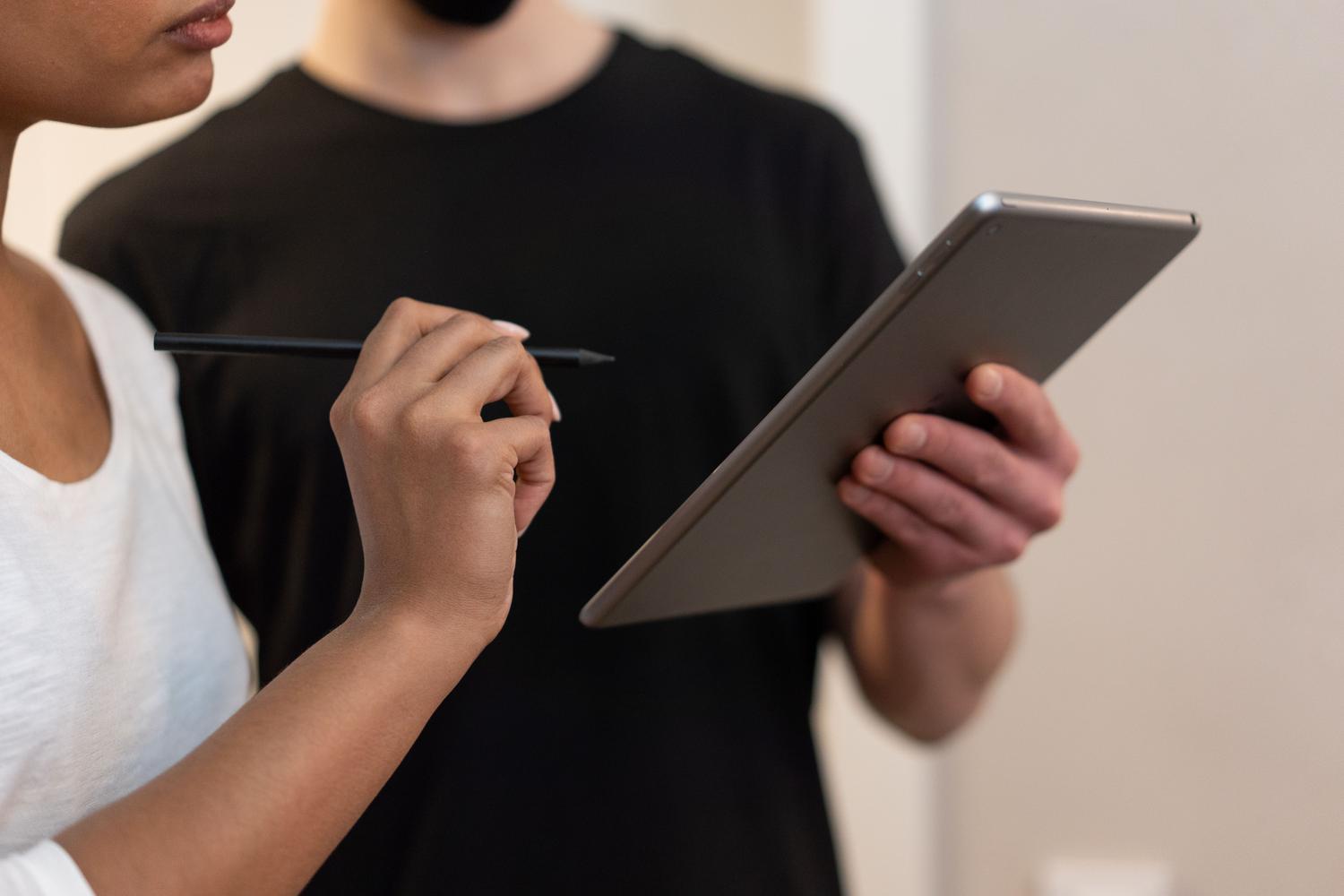 Dos profesionales colaborando en la revisión de un contrato digital utilizando una tablet.