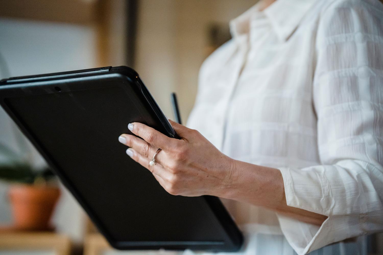 Primer plano de una persona profesional gestionando firmas digitales con una tablet y un stylus.