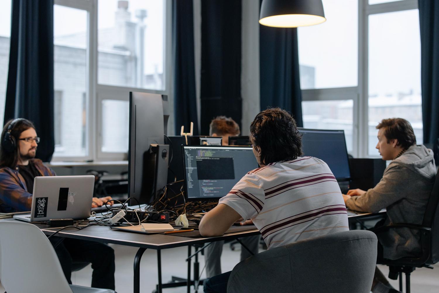 Equipo de ingenieros DevOps colaborando en una oficina tecnológica, ilustrando la cultura de trabajo necesaria para la orquestación de software.