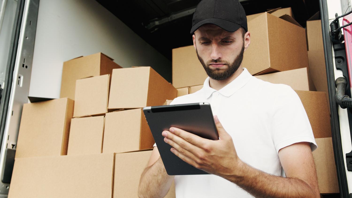 Trabajador de reparto gestionando envíos a través de una tablet, representando la integración del ERP con la distribución final y el transporte.