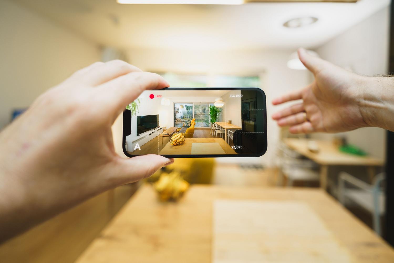 Uso de un smartphone para grabar un tour virtual interactivo de un apartamento moderno, ilustrando la digitalización de activos.