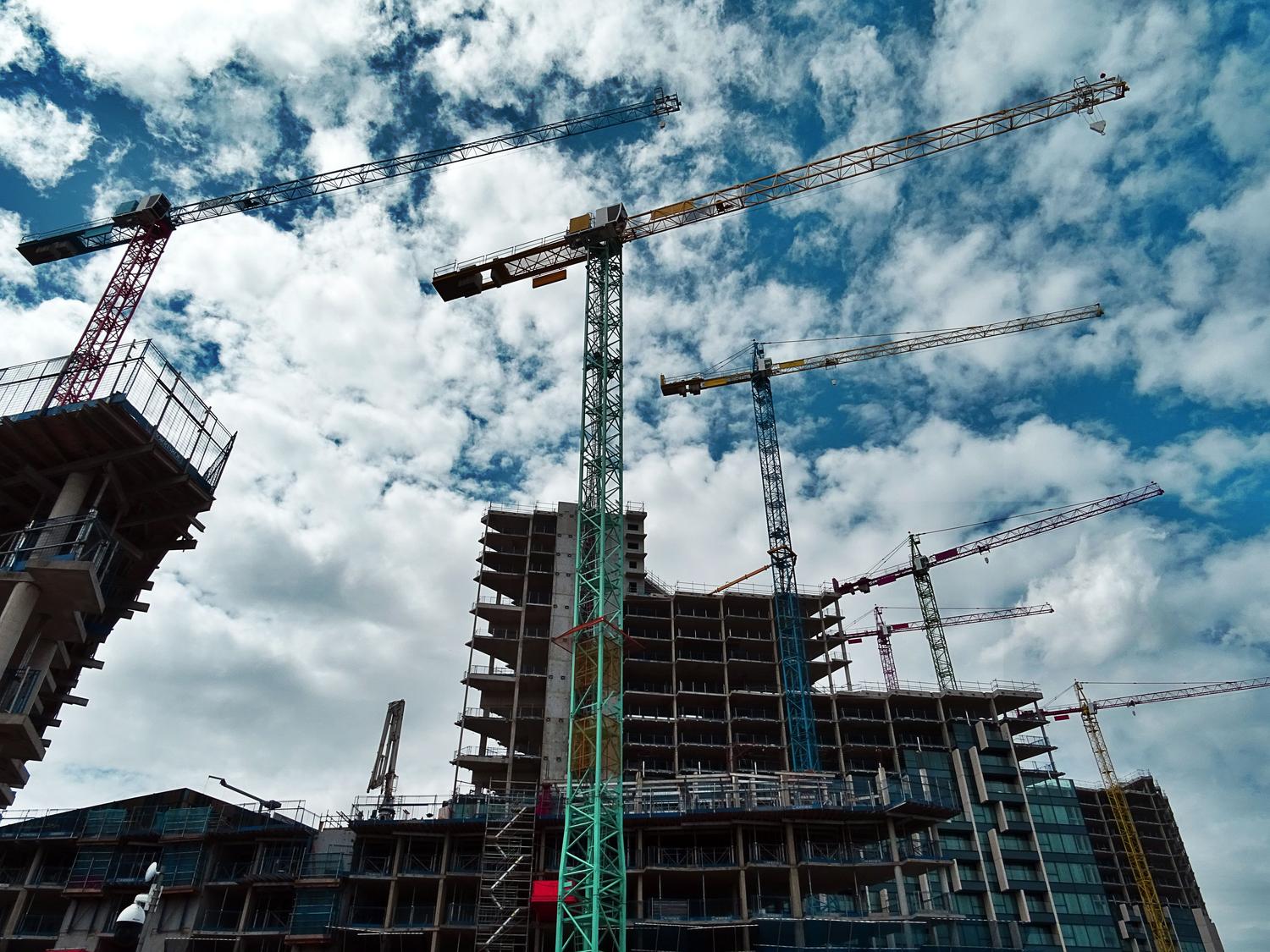 Vista de grúas y rascacielos en construcción en un entorno urbano, representando el sector ConTech y el desarrollo de activos inmobiliarios.