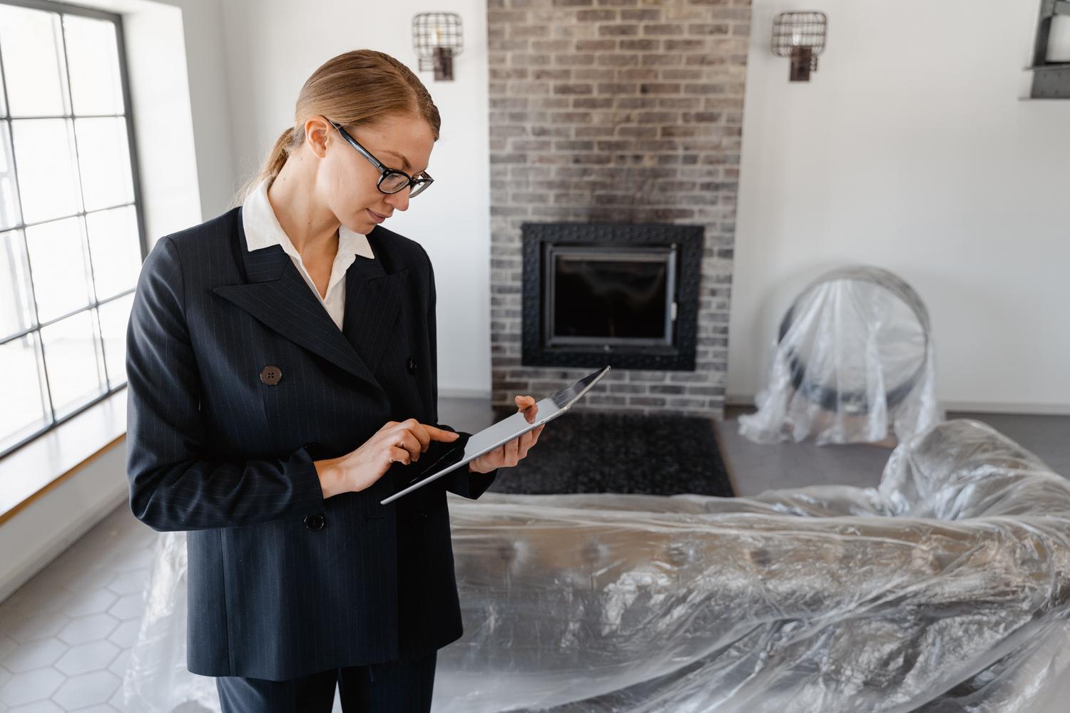 Profesional inmobiliaria utilizando una tablet digital para gestionar la administración de un activo inmobiliario en transición.