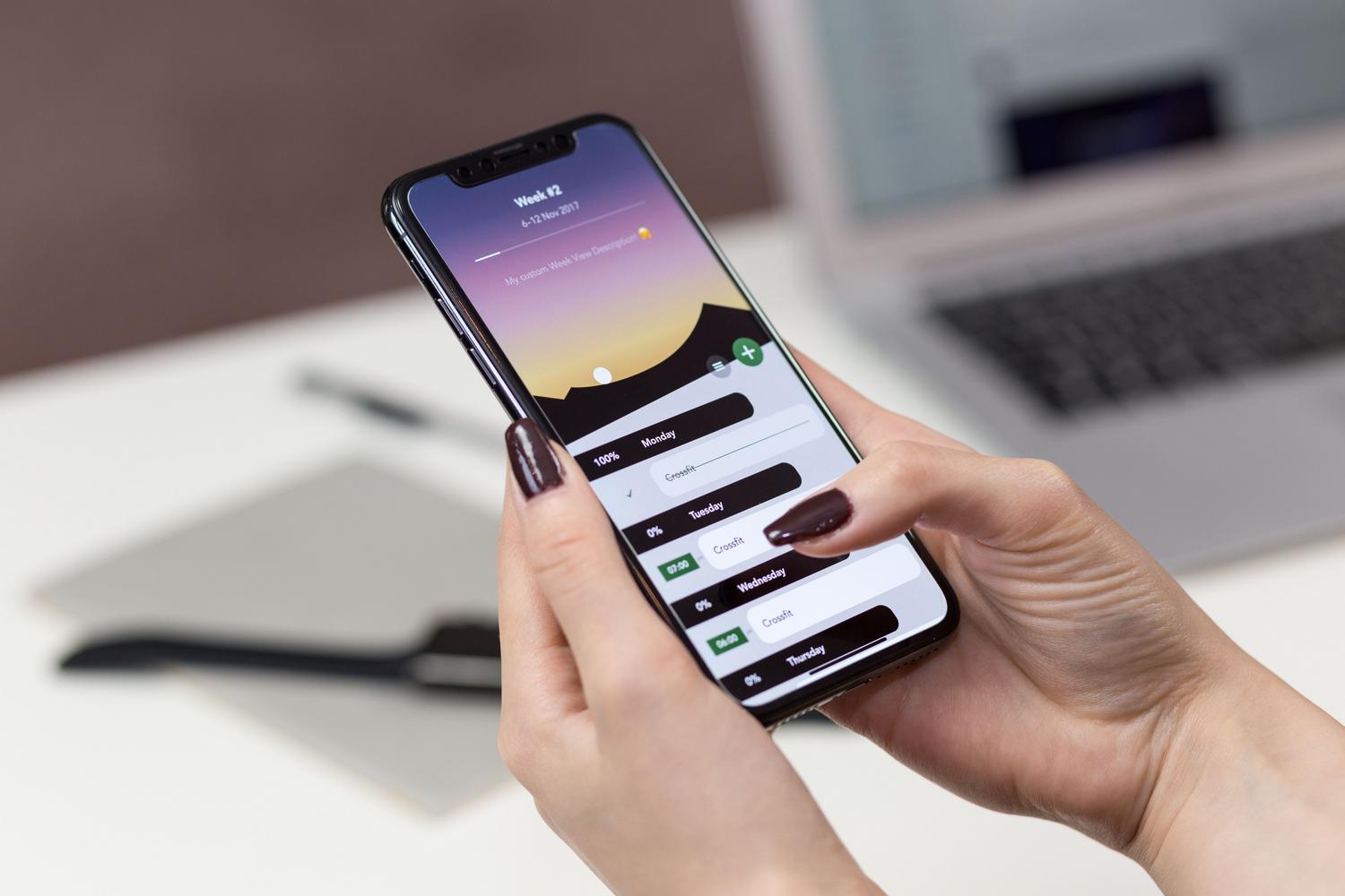 Persona utilizando una aplicación de registro horario en su smartphone dentro de una oficina, ilustrando la facilidad de fichar desde cualquier lugar.