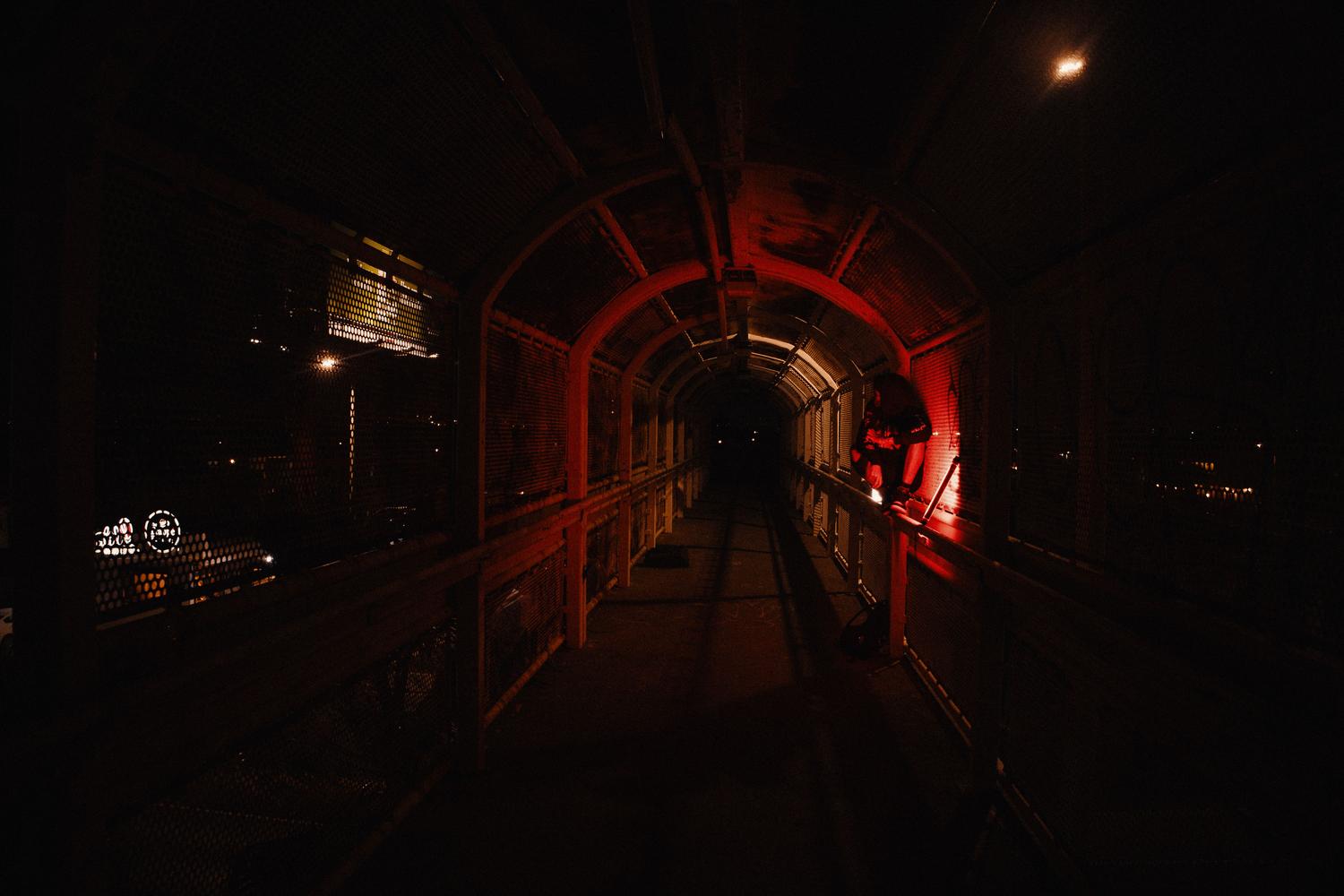 Pasillo industrial oscuro con luces rojas que evocan tensión y peligro en un entorno subterráneo.