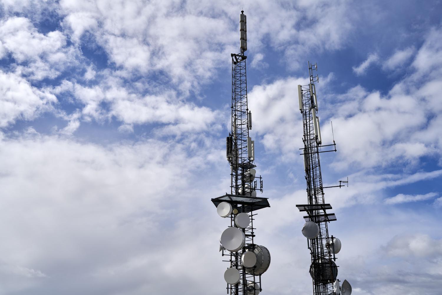 Torres de telecomunicaciones con antenas bajo un cielo nublado, representando la infraestructura de red móvil.
