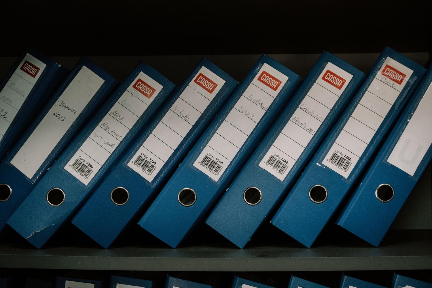 Carpetas de oficina azules organizadas en un estante, representando el concepto de la 'biblioteca de archivos' para usuarios Premium.