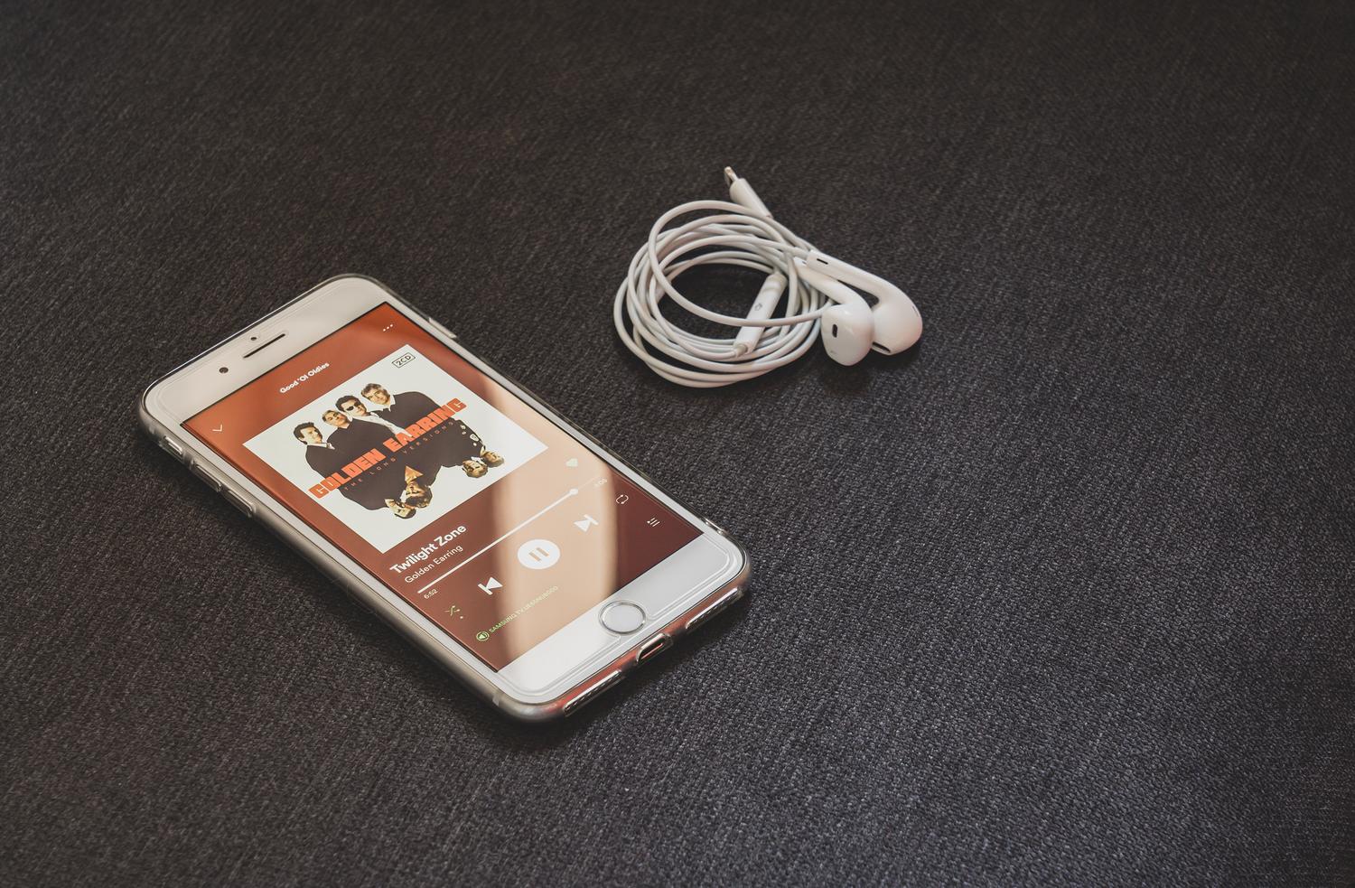 Smartphone moderno con auriculares sobre una superficie oscura, ilustrando la conectividad y el sonido de alta fidelidad. Smartphone moderno con auriculares sobre una superficie oscura, ilustrando la conectividad y el sonido de alta fidelidad.